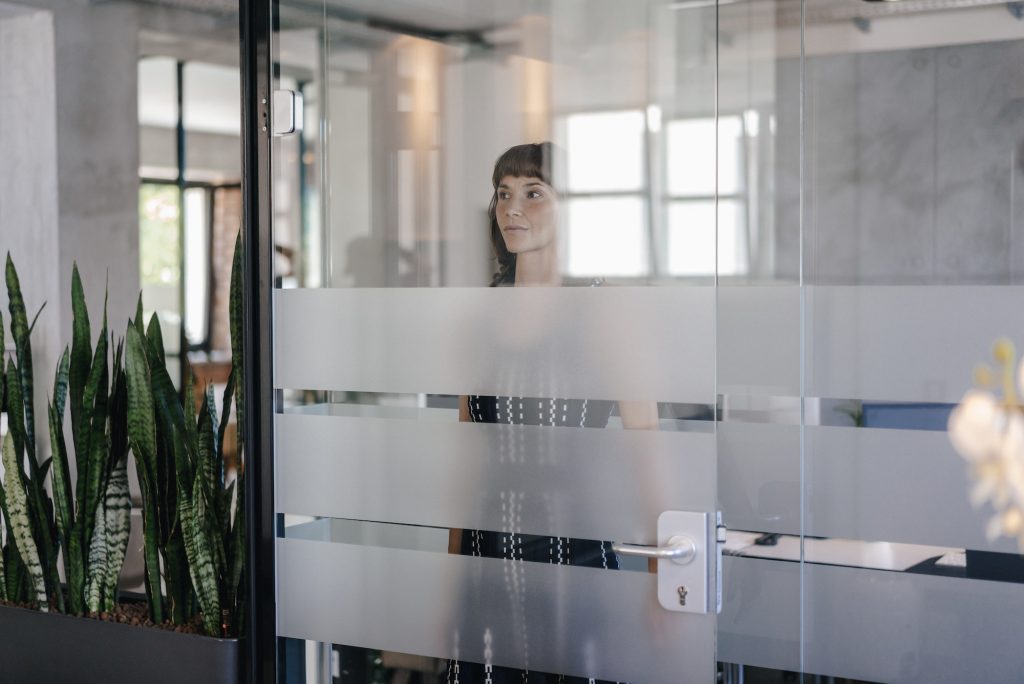 Businesswoman standing behind glass door